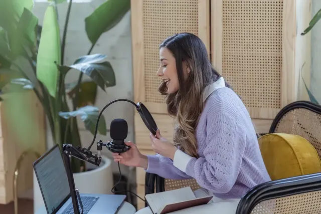 A woman recording a podcast at her desk surrounded by plants